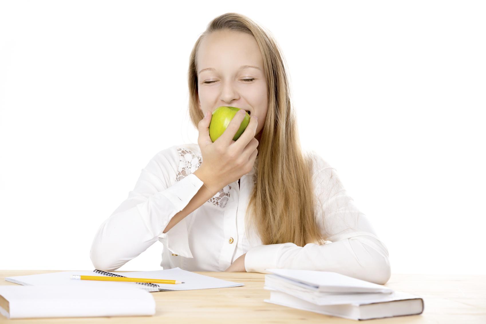 Cheerful schoolgirl eating apple