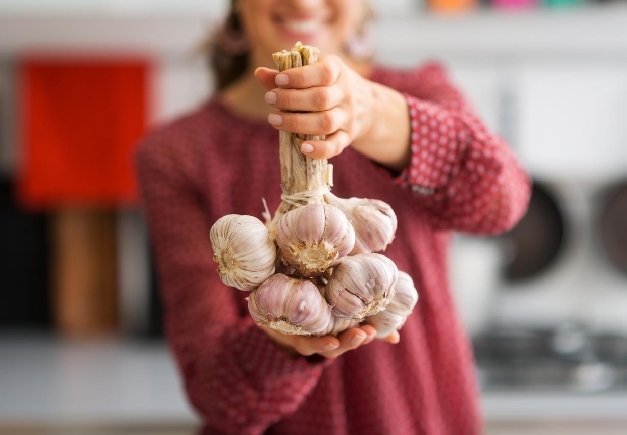 Closeup. Bunch of garlic held by woman