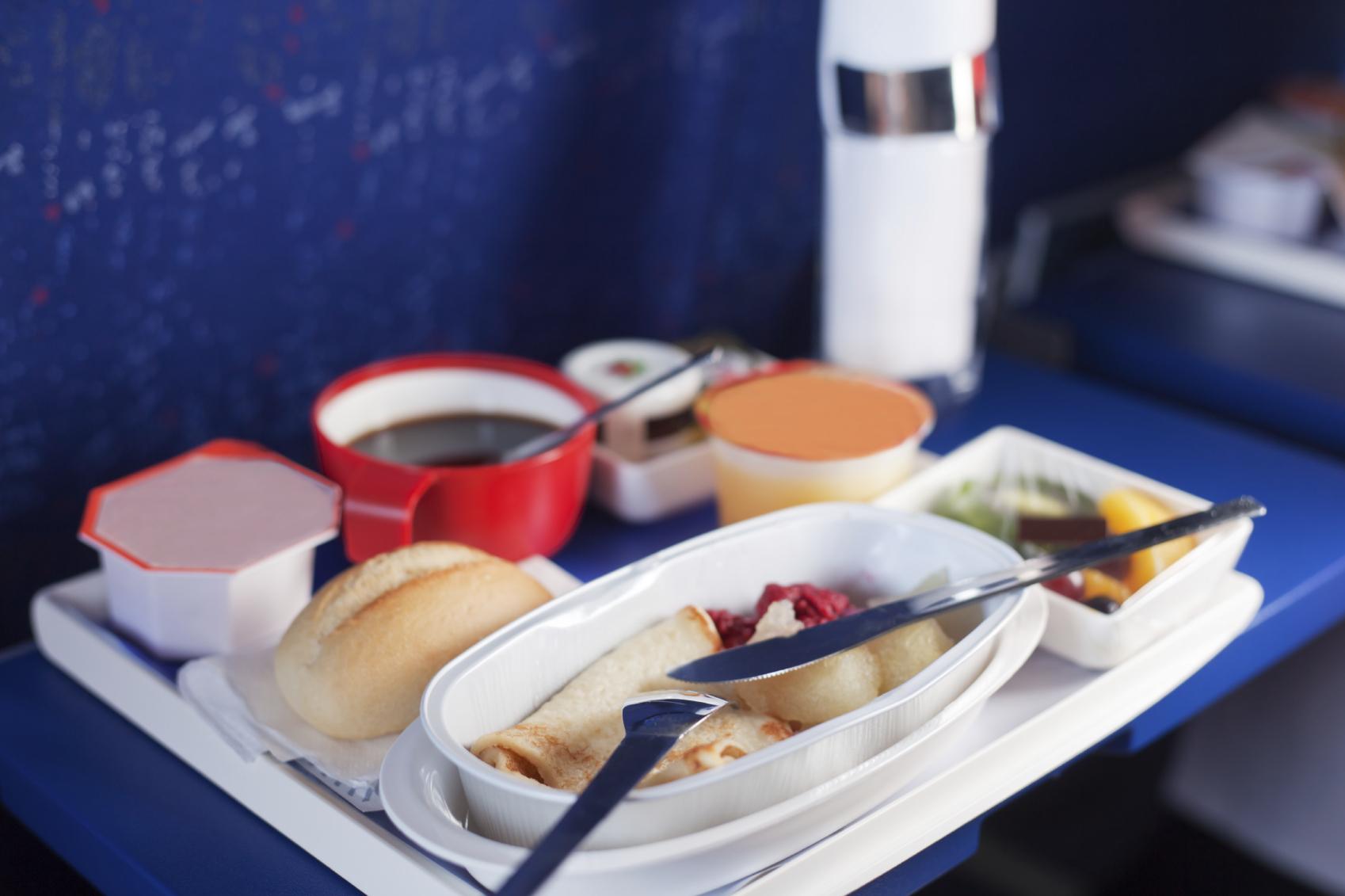 Tray of food on the plane. Focus on a plastic cruet stand with p