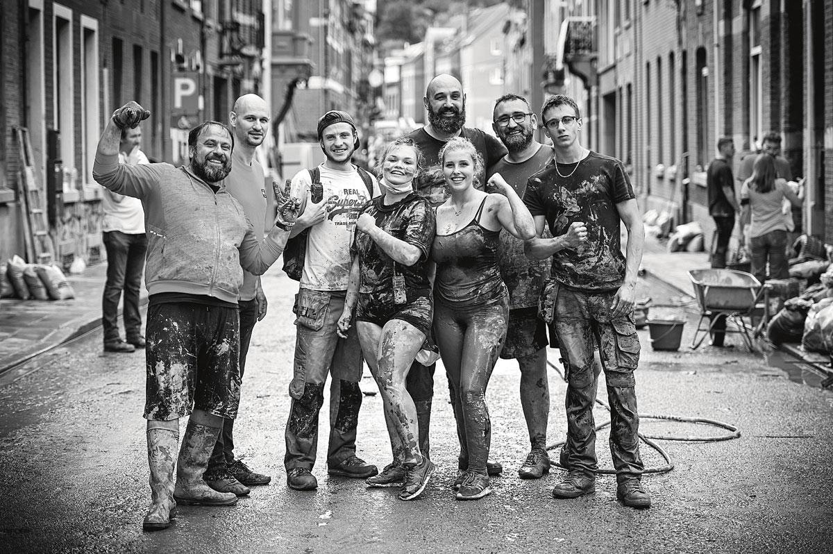 Couverts de boue, les habitants de quartier Bomel, à Namur prennent la pose alors qu'ils déblaient une rue.