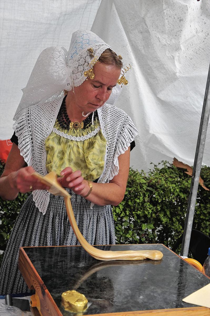 Une femme en costume traditionnel prépare des babelutes au beurre sur un marché.