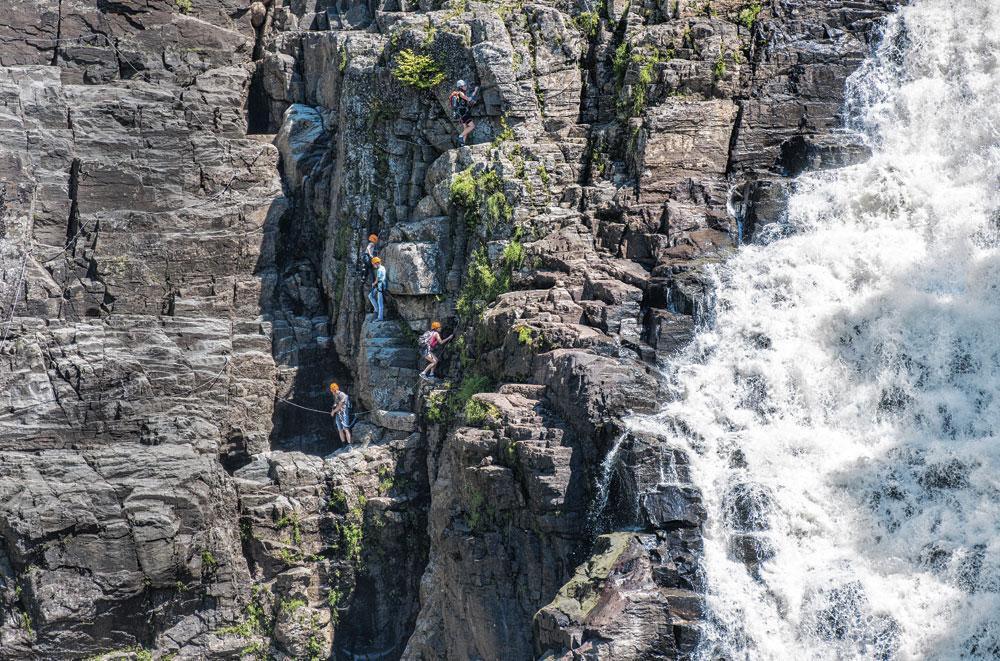 Wat beweegt daar tegen de bergwand? Even inzoomen. Het zijn klimmers die zich aan de via ferrata van de Canyon Sainte-Anne in het Canadese Quebec wagen.