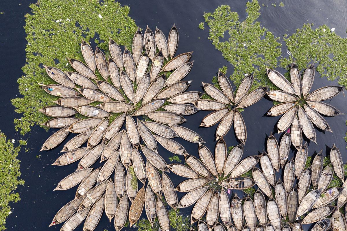 De bootjes die aangemeerd liggen aan de oevers van de Burungarivier in Bangladesh, doen denken aan reuzenlelies op het water.
