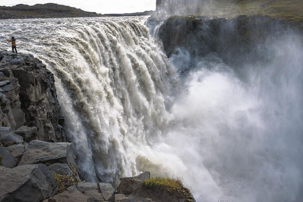 Een verwonderde toerist neemt een selfie aan de Dettifoss in IJsland, de op een na krachtigste waterval van Europa, na de Rheinfall in Zwitserland.