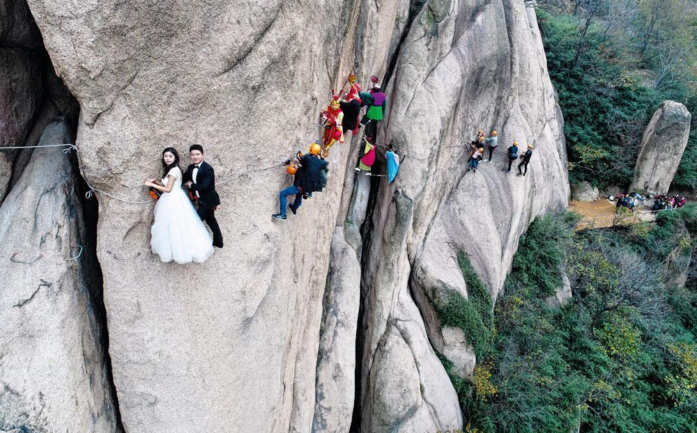 Dit Chinese paar poseert voor een originele bruidsfoto, hangend aan een klif. Alvast de kwade dagen even uittesten.