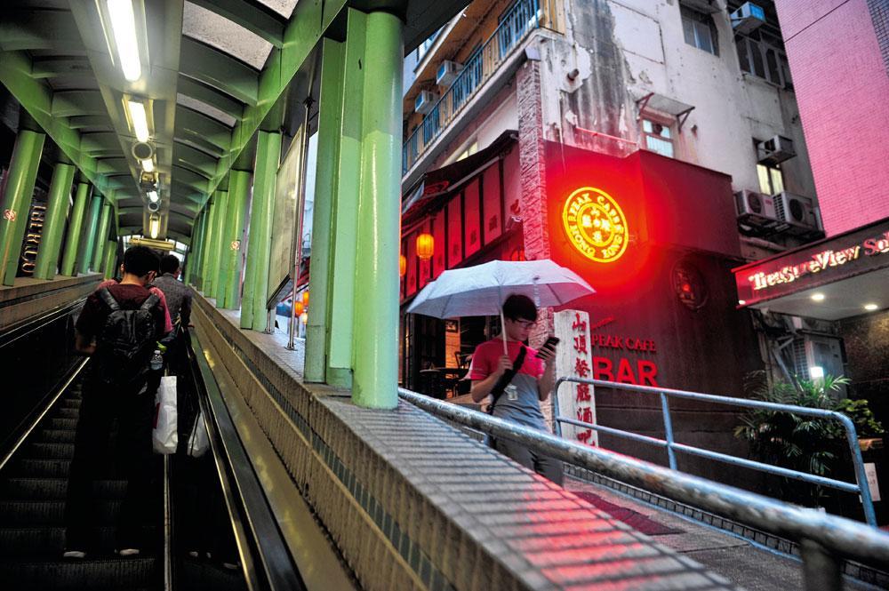 Le plus long escalator du monde (au centre) mène au quartier de Soho (en haut). Dans le centre (en bas) les centres commerciaux et les immeubles de bureaux monopolisent l'espace...