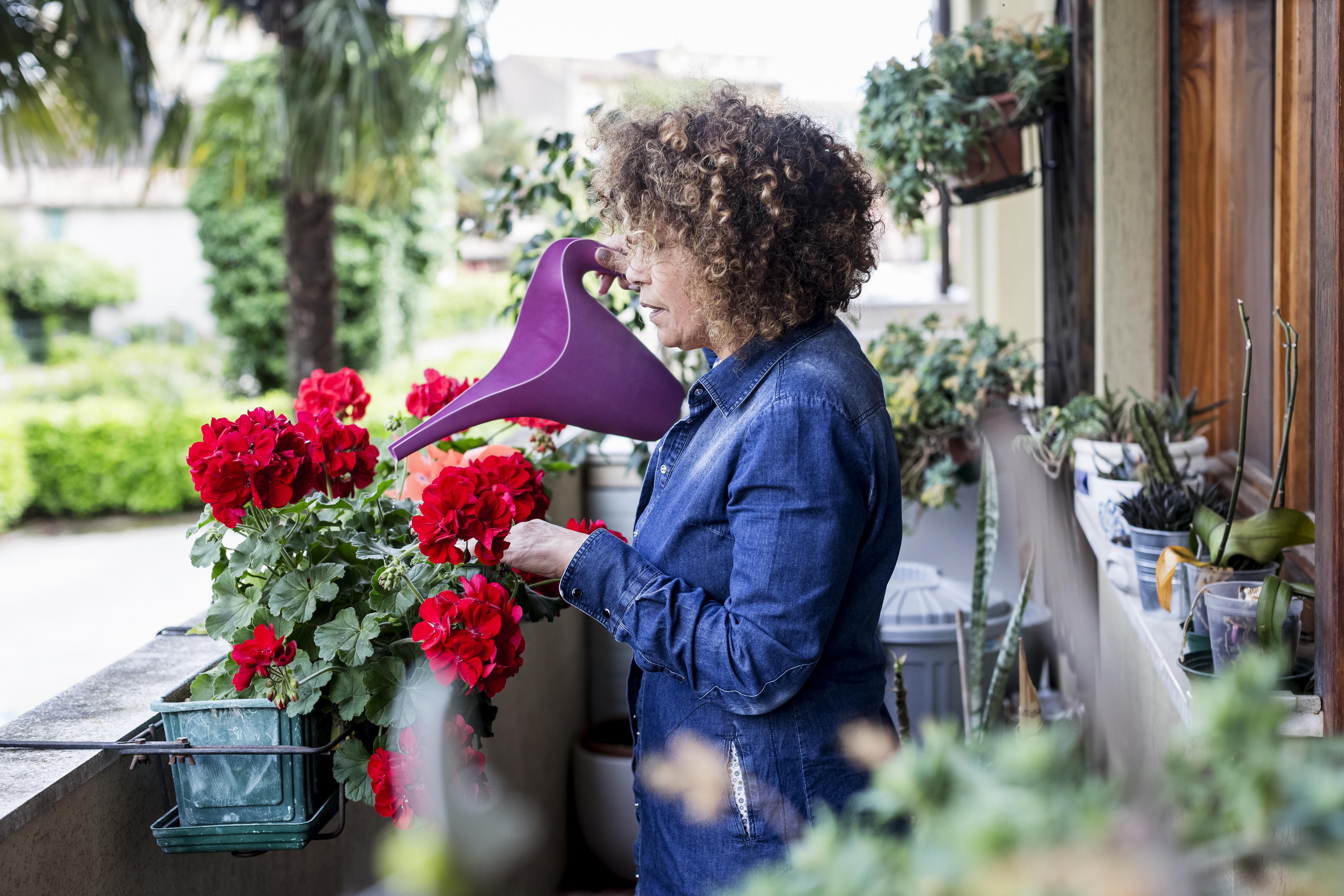 Vrouw geeft water aan planten op balkon