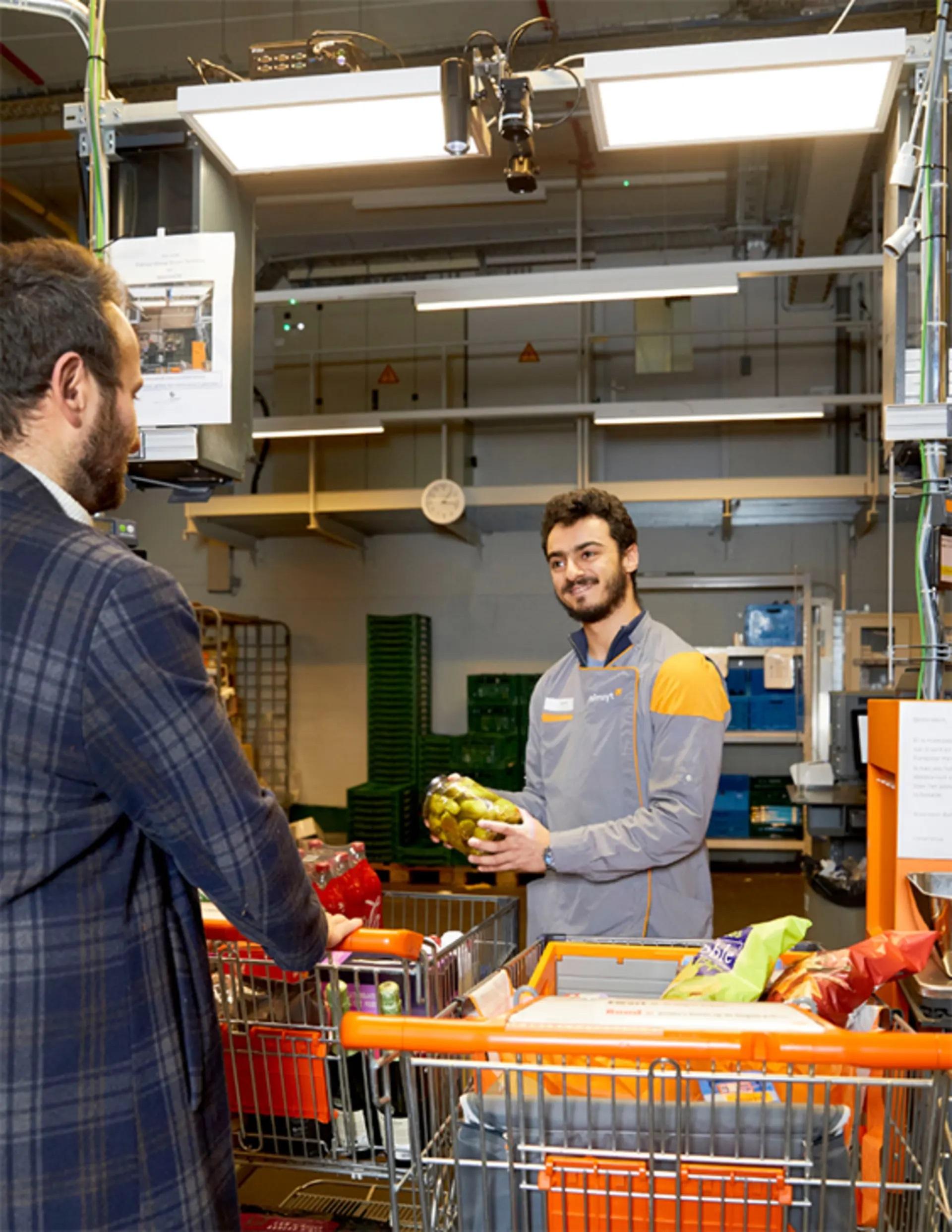 Colruyt-medewerker scant de boodschappen van een klant met het slimme kassasysteem