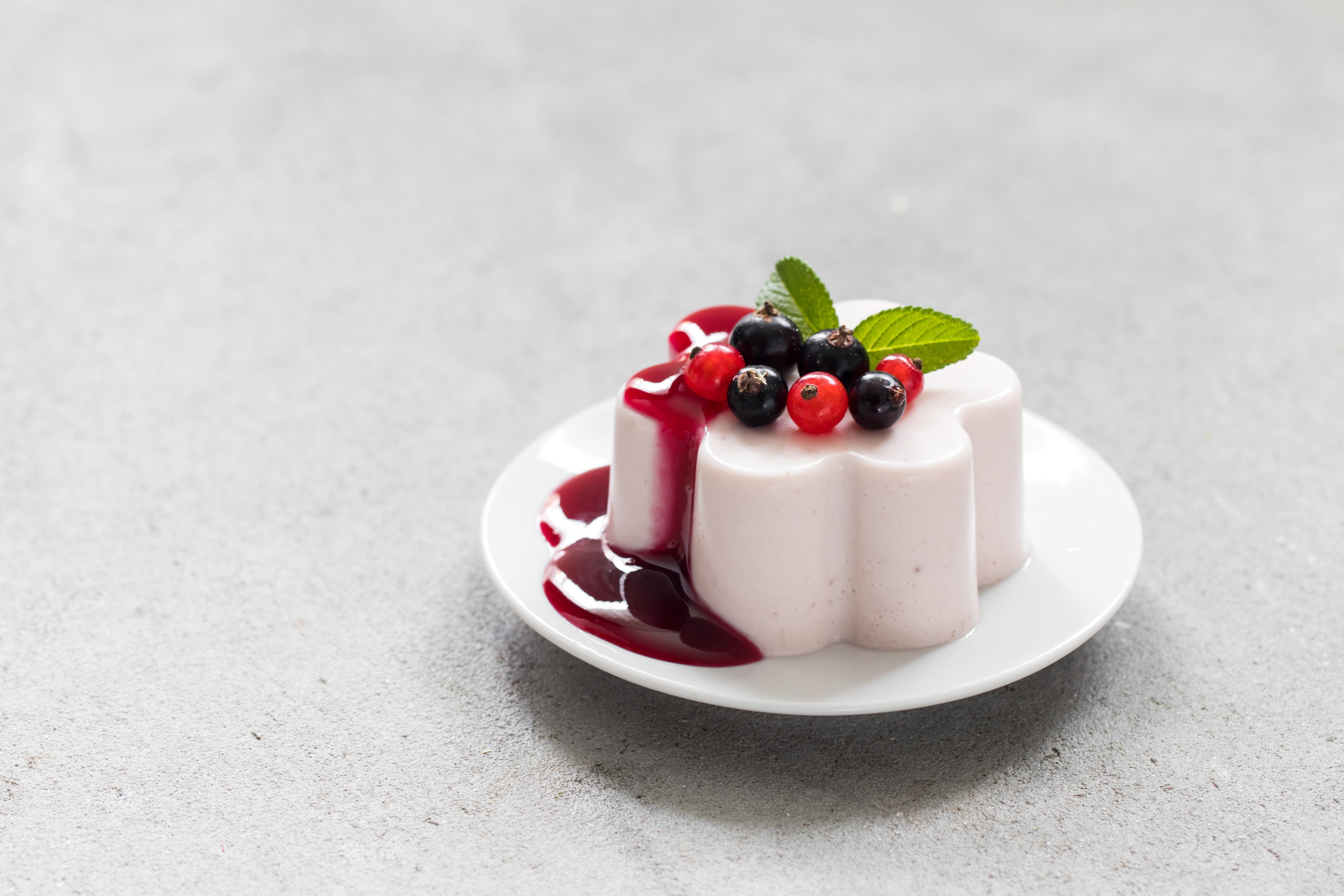 Red black currant Cream pudding, Panna Cotta. With red black currant sauce. On a plate. Light background. Close-up