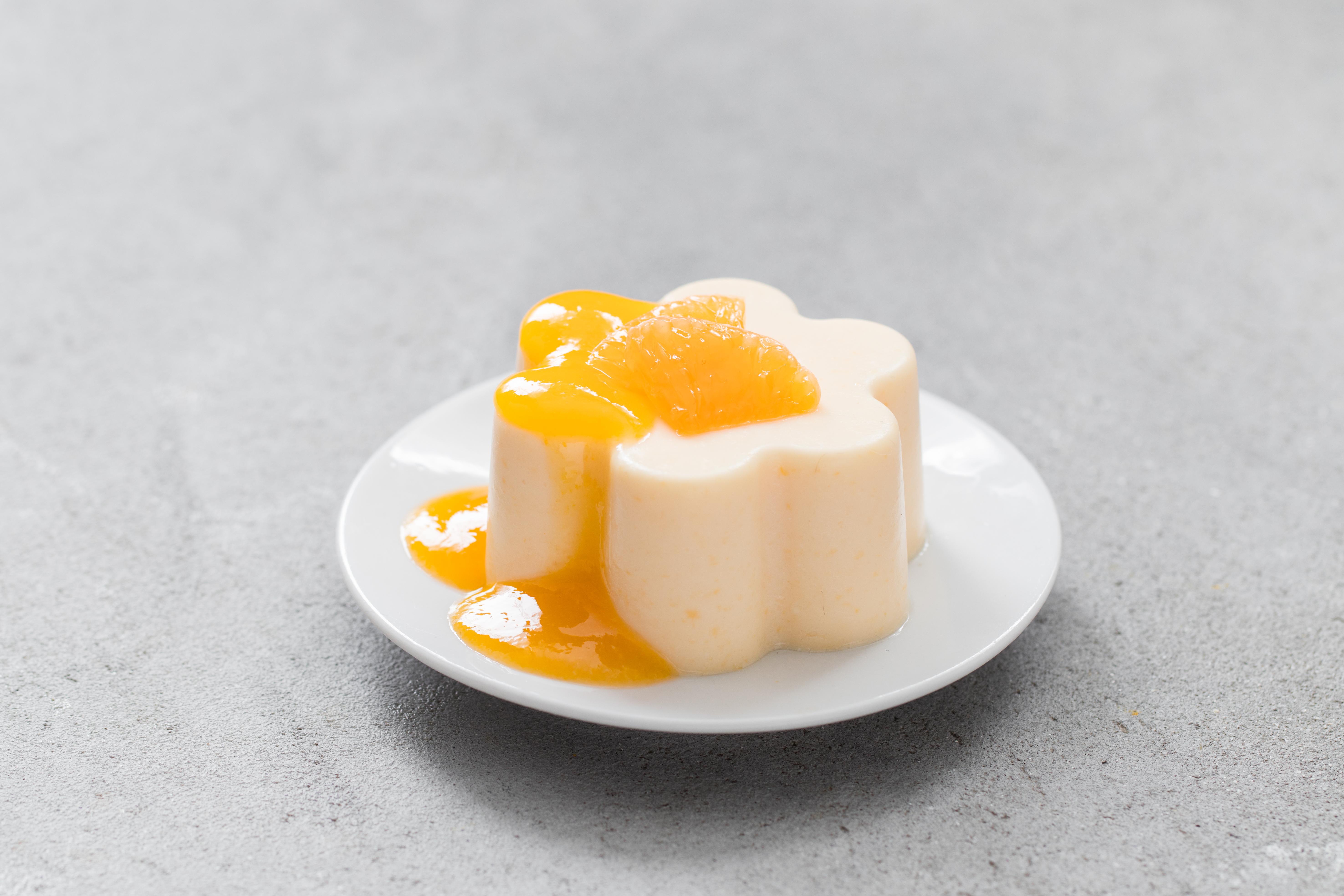 Vegan dessert. Tangerine Cream pudding, Panna Cotta witch tangerine sauce. On a plate. Light grey background.