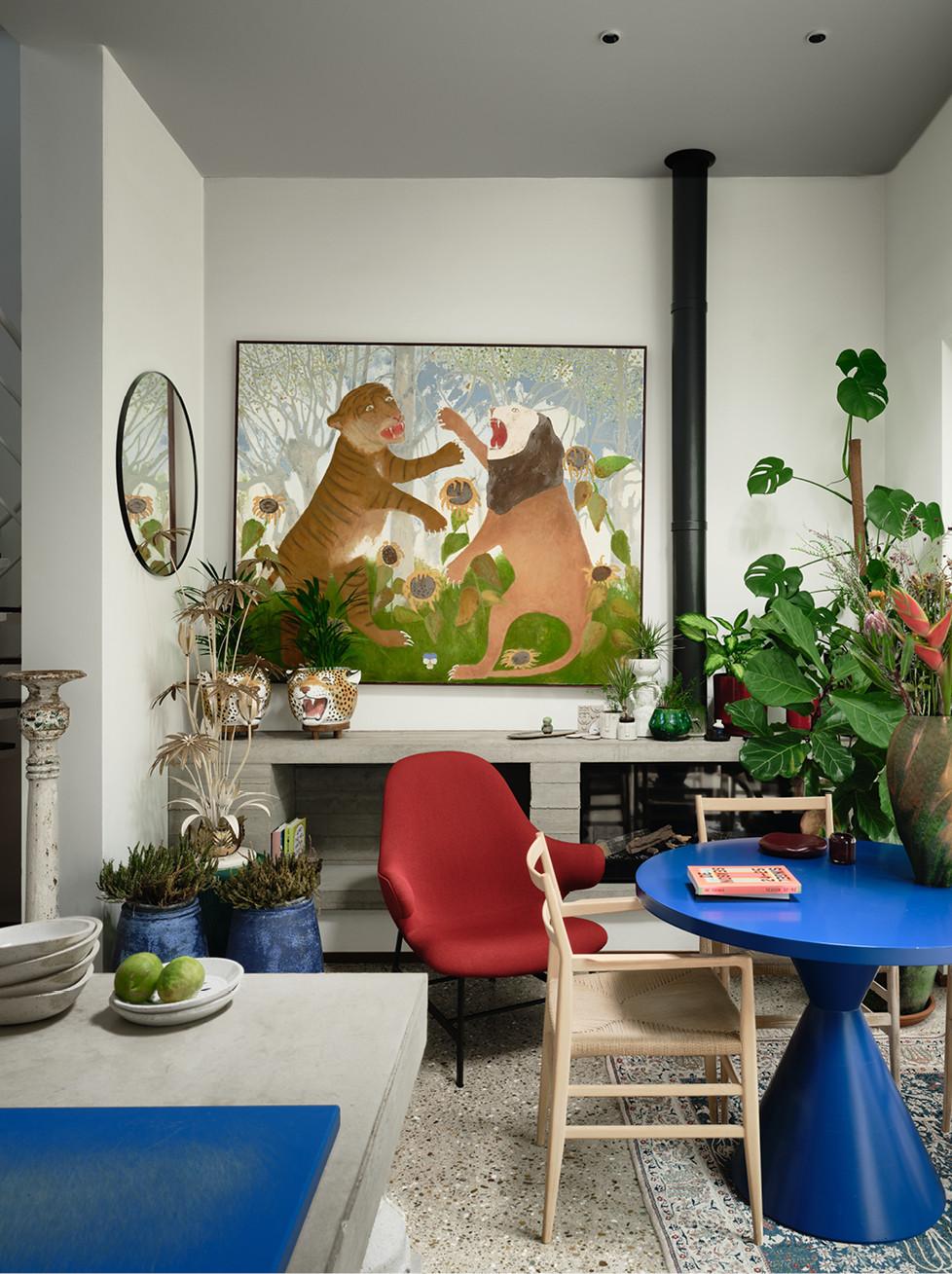 Boven de buffetkast springt een werk van Guy Rubicon in het oog. De plantenpotten in de vorm van tijgerhoofden zijn vintage, de keukentafel werd ontworpen door Contekst, de eettafelstoelen zijn van Cassina.