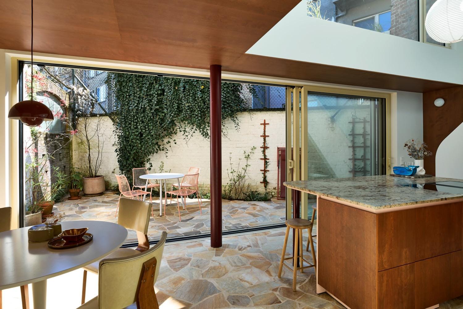 De blikvanger van de woning: voorheen een labo, nu een lichtrijke keuken plus eetruimte met vide. De mozaïek van terrastegels loopt naar binnen, waardoor het stadskoertje onderdeel wordt van het interieur.