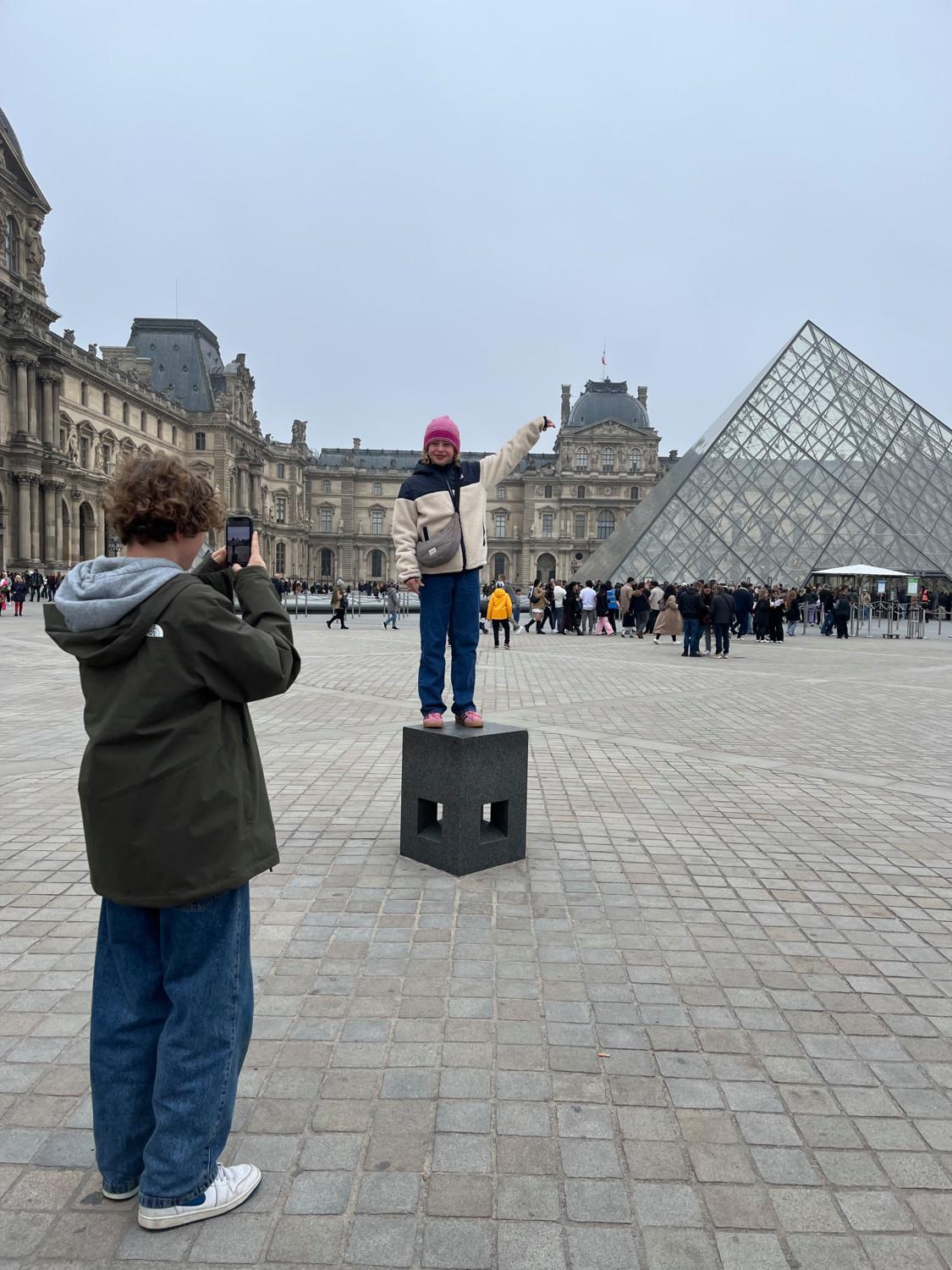 Een foto van de tienerkinderen van Libelle-redactrice Annelies. De dochter poseert bij de piramide van het Louvre, de zoon neemt de foto.