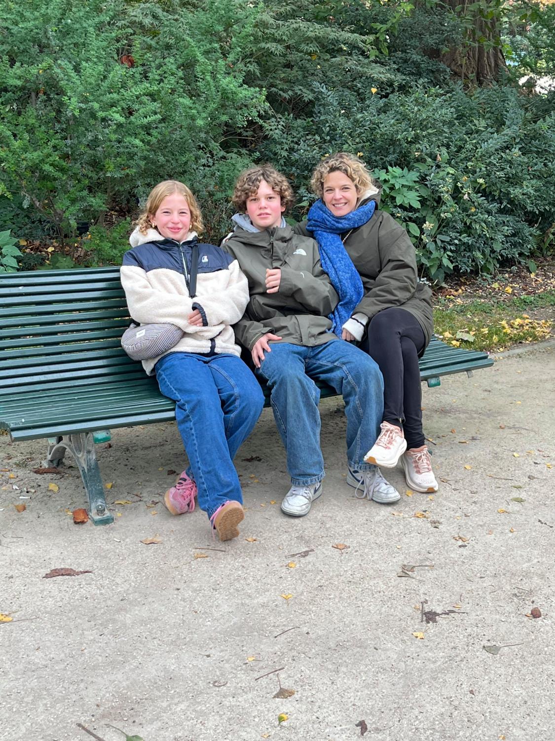 Een foto van Libelle-redactrice Annelies samen met haar twee kinderen op een bankje in Parijs.
