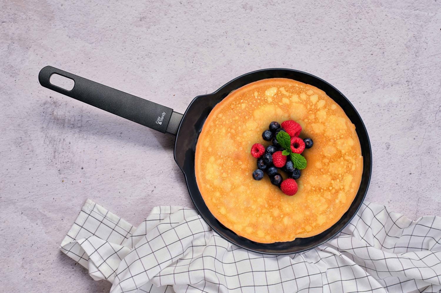 Een pannenkoekenpan met een pannenkoek en bosvruchten in.