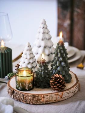 Zet verschillende soorten kerstbomen in allerlei materialen (ook kaarsen) op een houten boomschijf als pronkstuk op tafel.