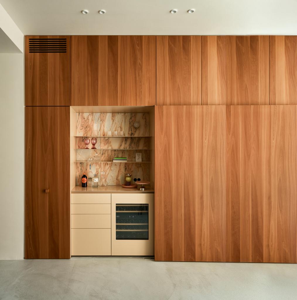 De plafondhoge wandkast in perenhout verbergt een barkast in Rose Aurore marmer en émaille.