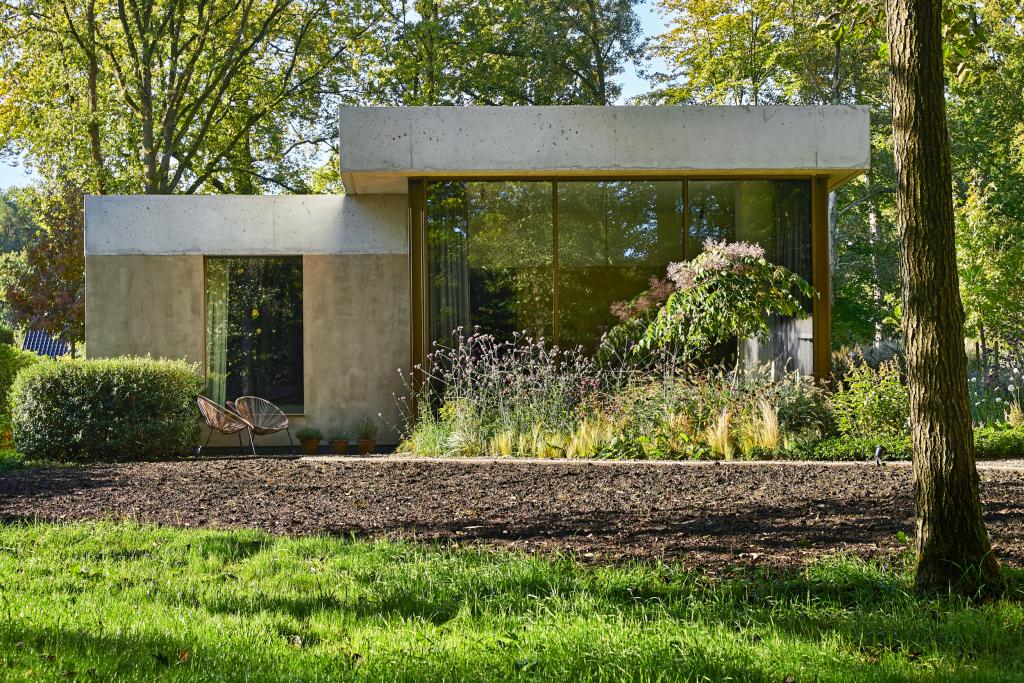 Het koppel wilde een huis dat in de groene omgeving zou opgaan. Daarom benadert het gekleurde beton van de muren, zowel binnen als buiten, de kleur van de boomstammen in de tuin.