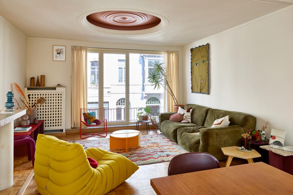 De klassieke luster verdween, de rozet kreeg een kleurtje. Tussen de vintage meubelen ook enkele ontwerpen van Lies, zoals het tv-meubel en de bijzettafeltjes. Het wandtapijt is van BFGF., Togo Ligne Roset, Bold Chair Moustache