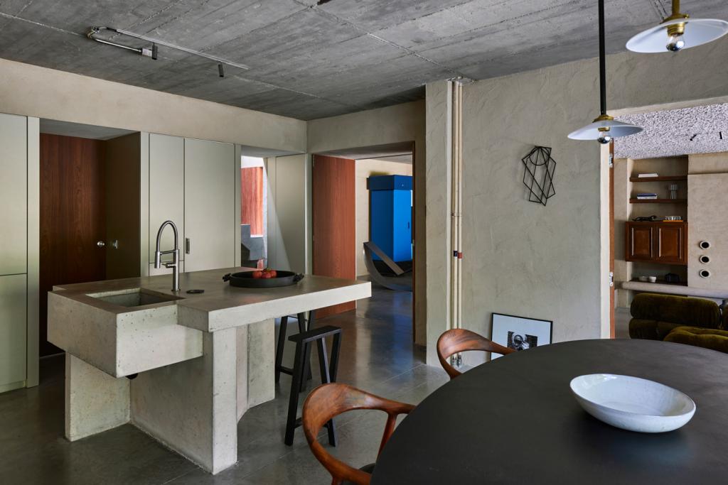 De wandkasten zijn bekleed met goudkleurige Fenix. Het kookeiland en aanrecht zijn ter plekke in beton gegoten. Let op de deconstructivistische details in de geest van Martin Margiela.