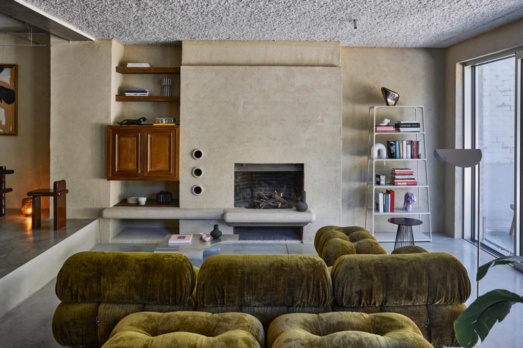 Het mosgroene Camaleonda-sofa-eiland zorgt voor een dosis kleur in de woonkamer, de eikenhouten kast naast de haard is nog de originele drankenkast van de woning.