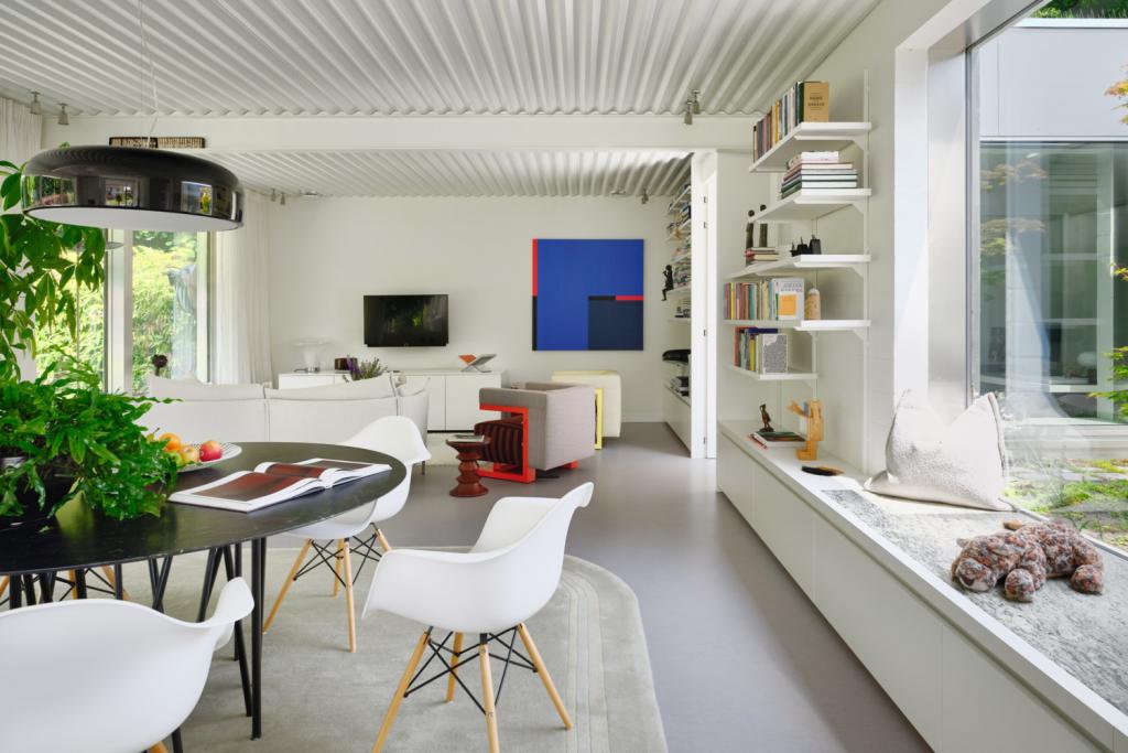 Lichtrijke woonkamer. Om de grens tussen binnen en buiten verder te laten vervagen, werd de aluminium bekleding doorgetrokken op de dagkanten van de ramen.