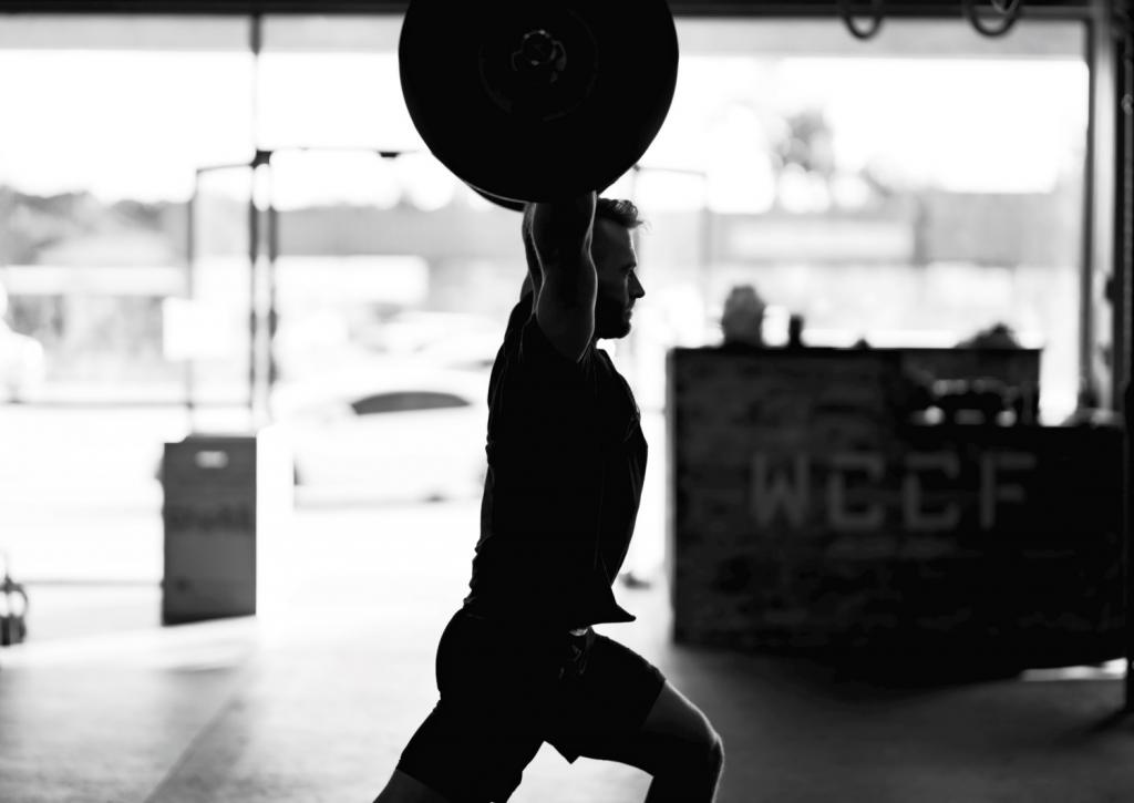 Zwart-wit foto van man die aan gewichtheffen doet.