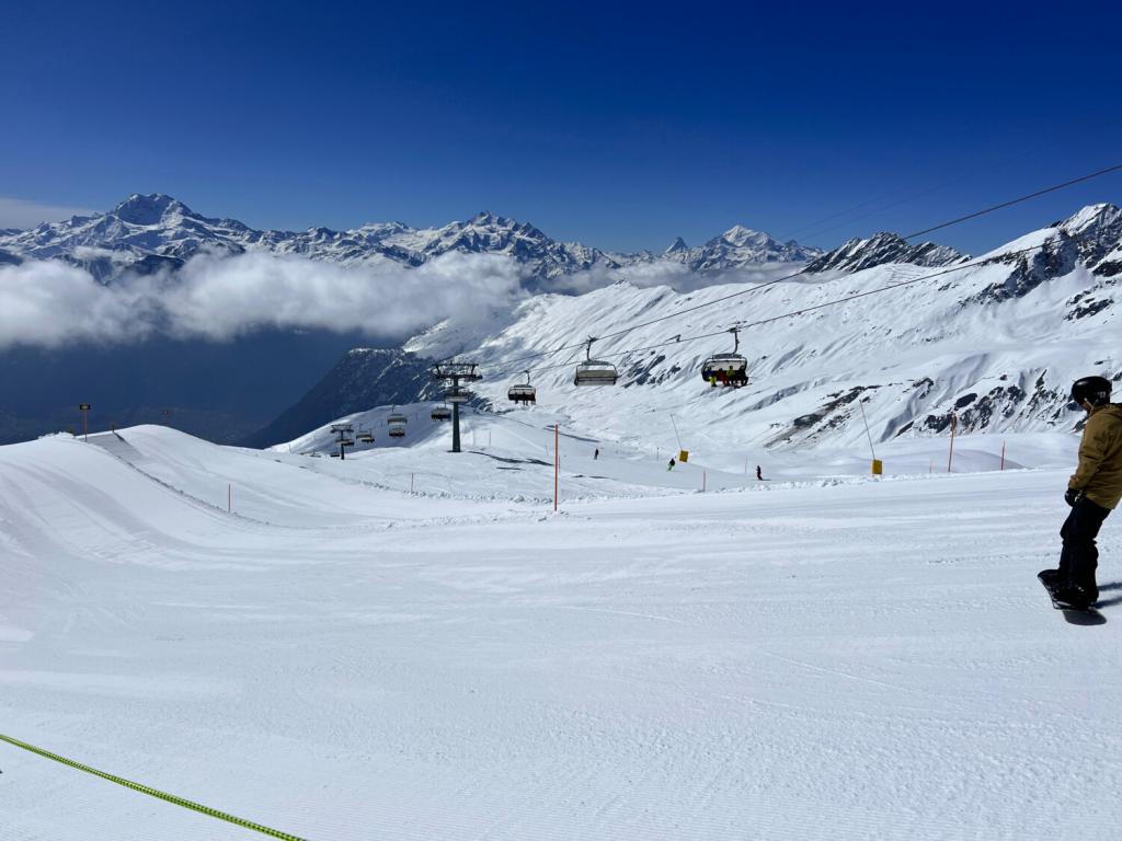 Snowboarder op de skipiste met uitzicht over de vallei en skiliften.