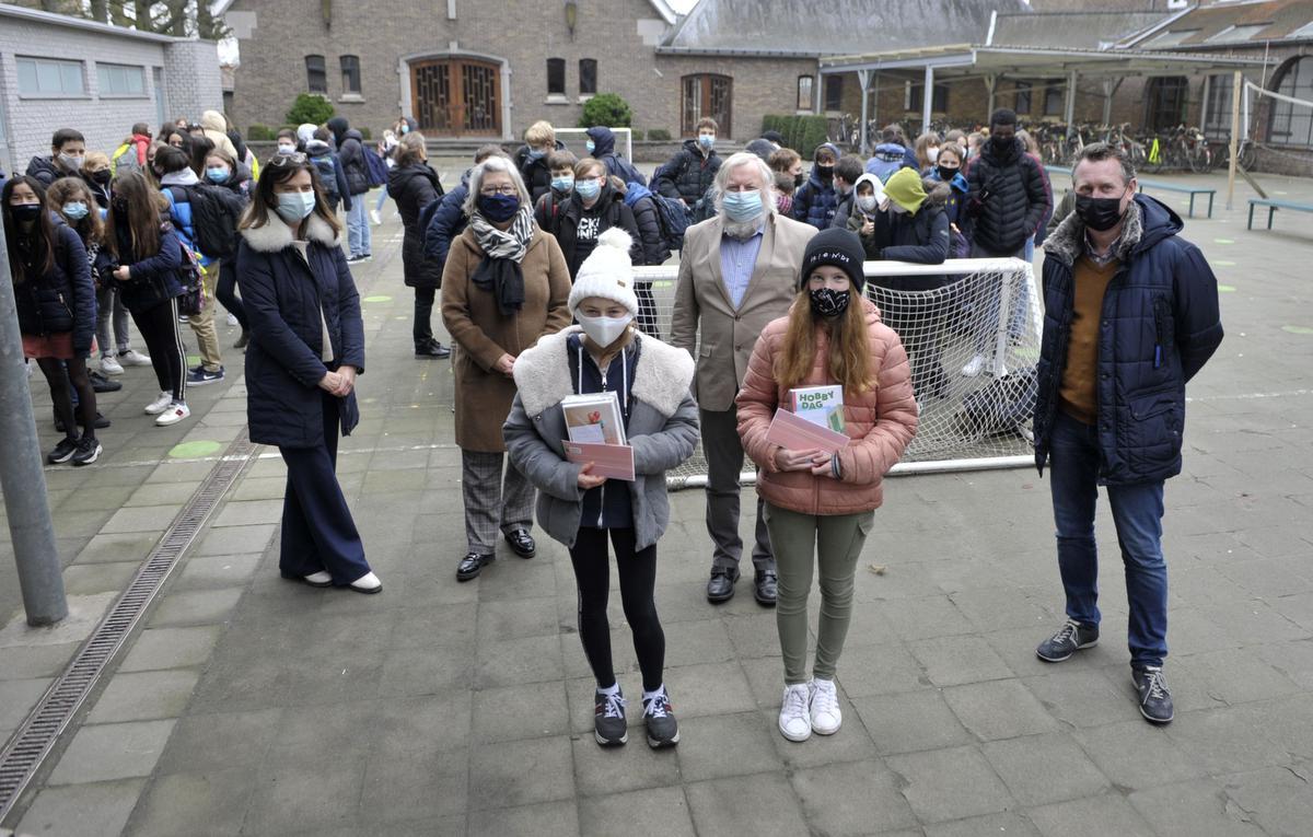 In Prizma Middenschool kreeg de tweelingzus van winnares Kayeleigh Vande Vijver de geschenken aangeboden, want haar zus was afwezig. Ook winnaar Naomi Clinckemaillie staat op de foto net als Catherine Callu (Davidsfonds), schepen Jean-Pierre Deven, burgemeester Kurt Windels, Mieke Berghman (directeur Prizma Middenschool) en diverse leerlingen.© (Foto FODI)