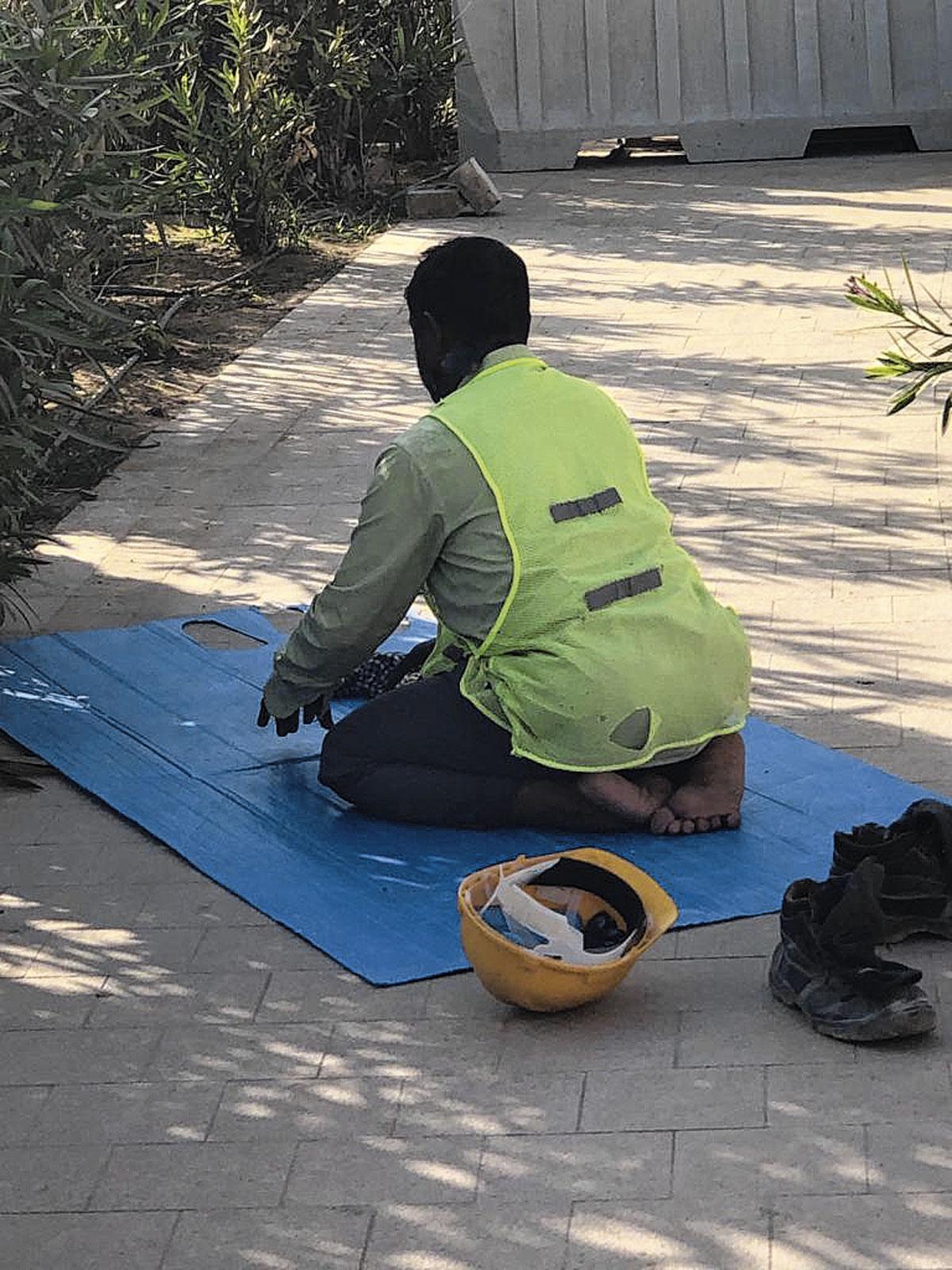 Een gastarbeider onderbreekt zijn werk om te bidden in de Pearl, een luxueuze buitenwijk op een kunstmatig eiland nabij Doha.