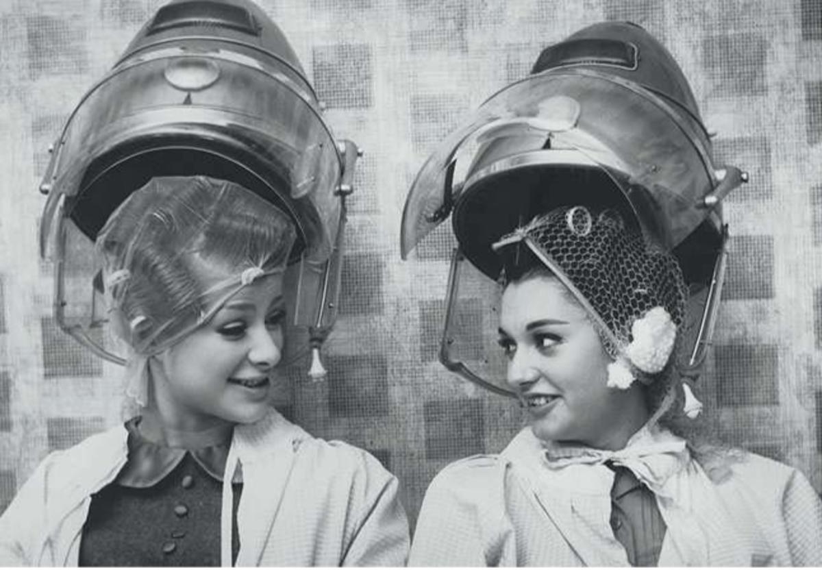 Een van de populairste vormen van de krul als versiering is de permanent-haardracht die vooral vrouwen toepassen. Agneta Malmgren (links) en Maria Madronero in de aanloop tot de Miss Worldcompetitie, november 1964. (Foto Roger Jackson/Getty Images)