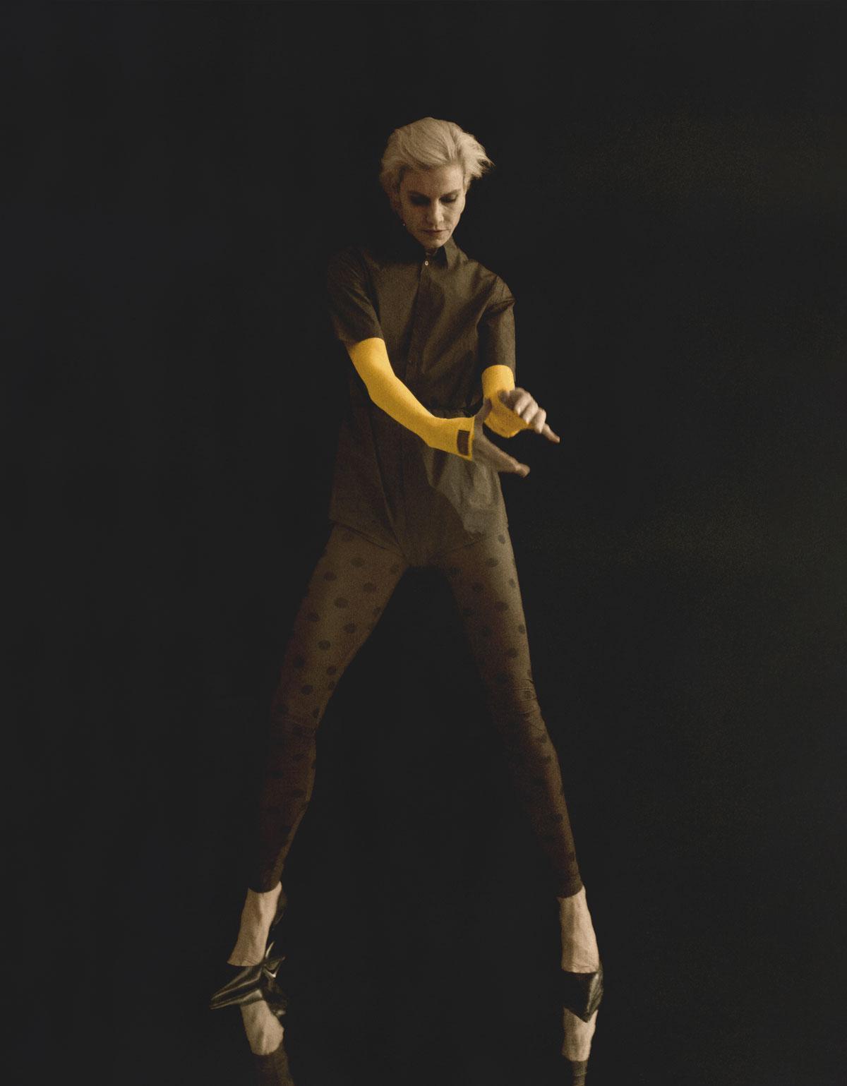 Katoenen hemd met romperafwerking, gele nylon top, bruine nylon legging met stippen en zwartleren sleehakken, alles Raf Simons.