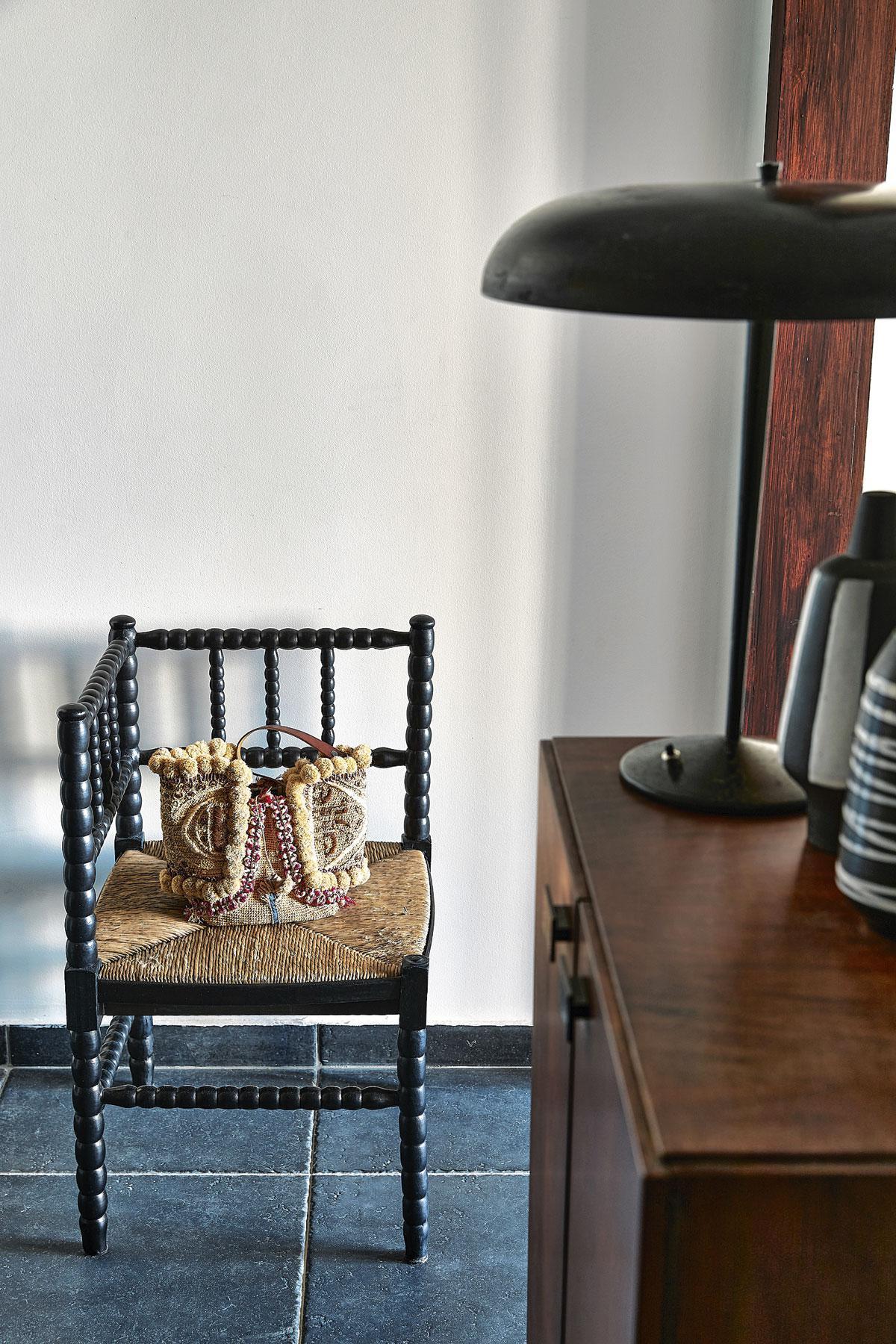 L’habitante aime les contrastes noir et blanc. Elle a habillé de cuir cette ancienne Corner Chair britannique, dénichée au Sablon. Ce sac en raphia est une trouvaille à Paris, où elle a longtemps vécu et travaillé.