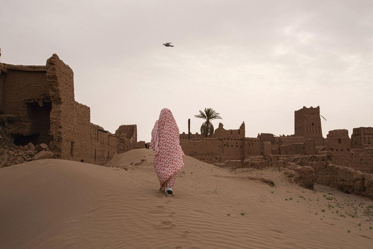 La marche des dunes Une jeune femme se promène parmi les ruines de Ksar Bounou, un village progressivement englouti par l’avancée du désert.