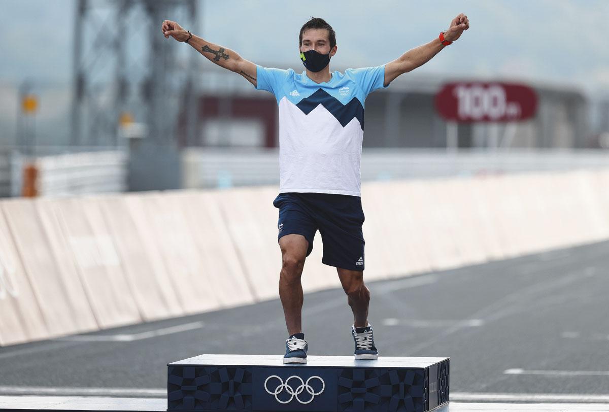 Na zijn gouden medaille in de tijdrit op de Spelen van Tokio betreedt Roglic het podium met een typische schansspringpose.