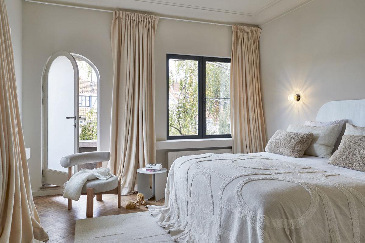 Op het bed ligt een sprei van H&M Home, het tapijt komt van Maisons du Monde en de stoel van H&M Home. De wandlamp is een vintage exemplaar van Cosack.