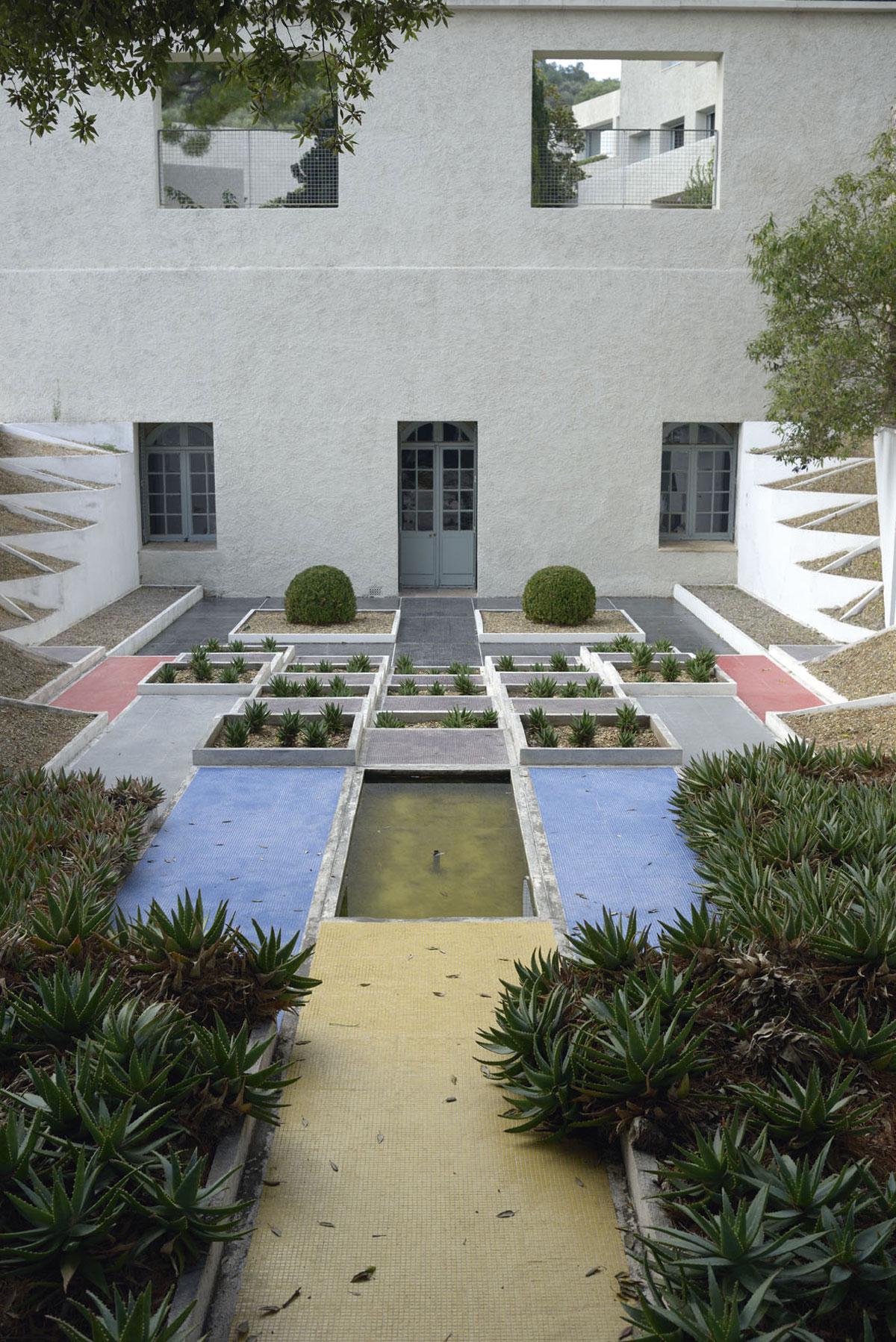 De kubistische tuin bestaat uit een dambord van getrapte vierkanten. De paden zijn bedekt met kleurrijke mozaïeken.