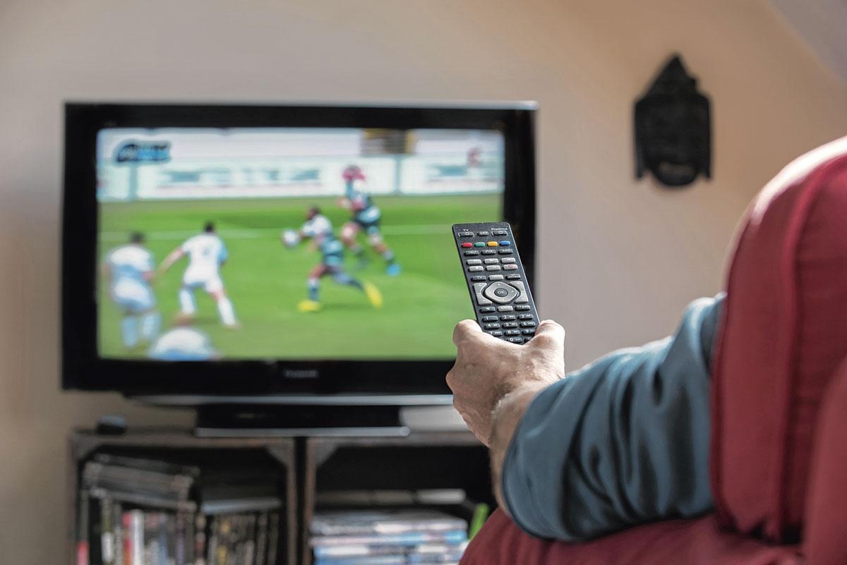 Personne dans son fauteuil matant un match de foot à la télévision