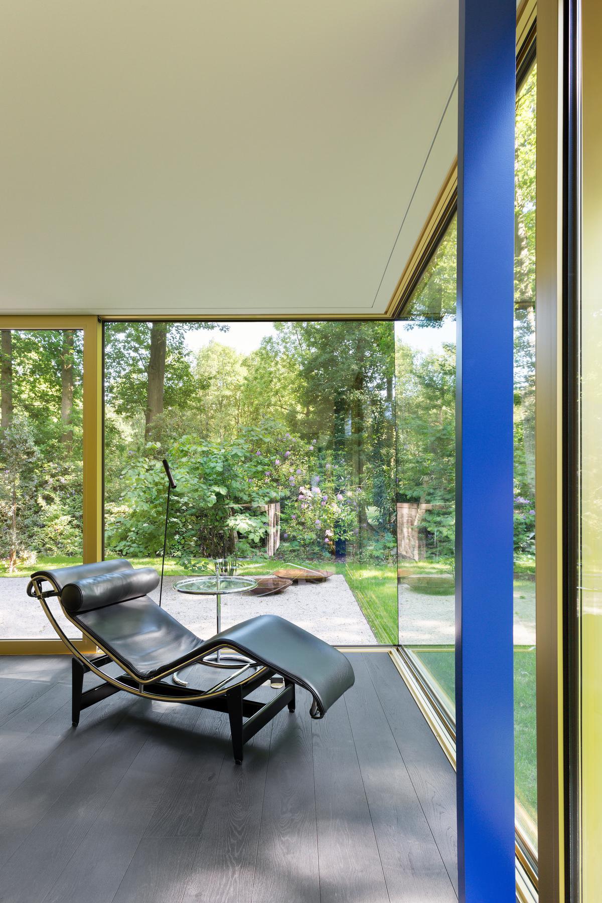 De leefruimte is volledig op de tuin georiënteerd, met glaspartijen van 16,5 meter lang. Gouden geanodiseerde raamprofielen omarmen de relaxte setting en de chaise longue van Le Corbusier.© Giulia Frigerio
