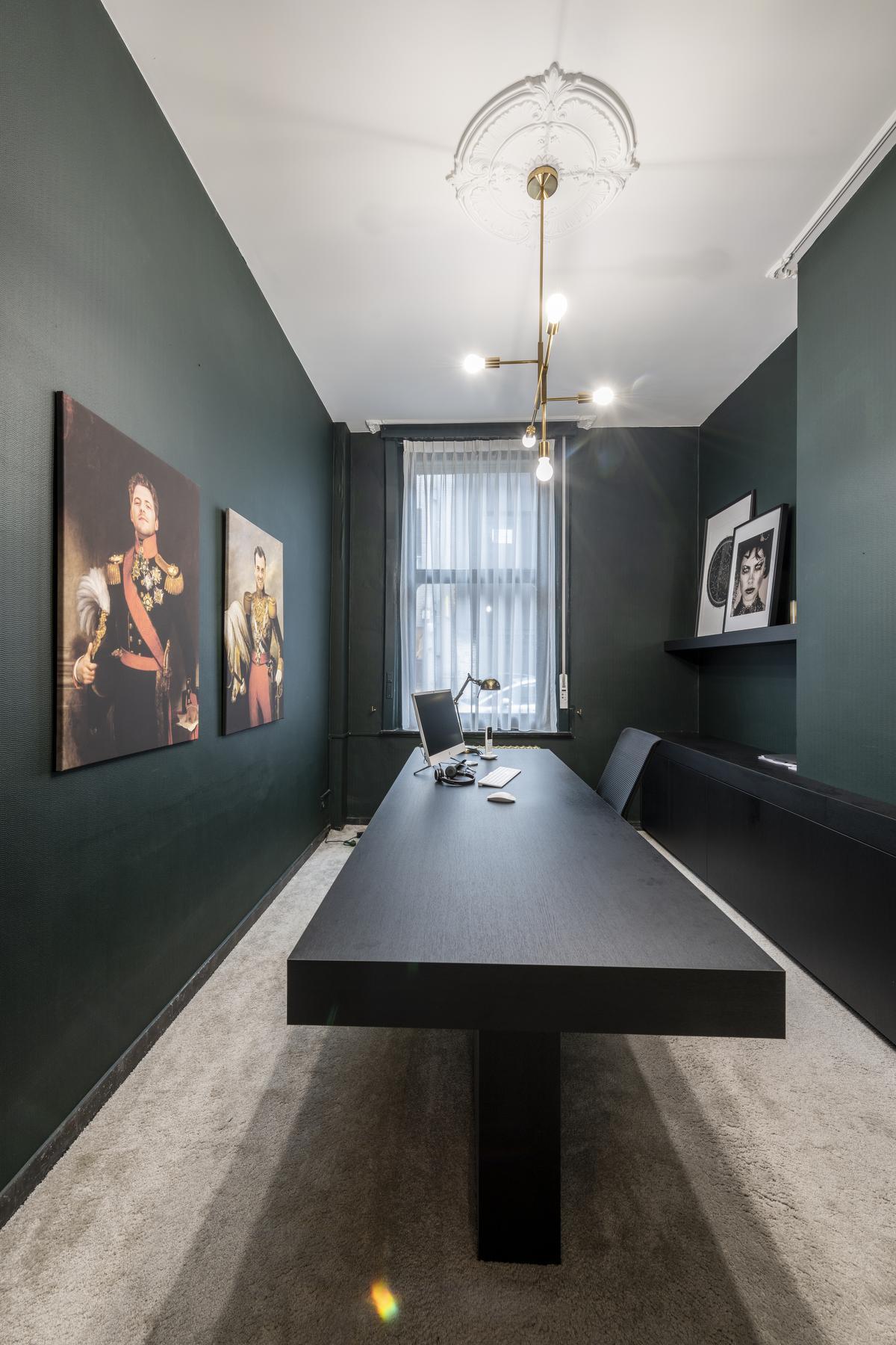 Het strakke bureau combineert mooi met de ornamenten aan het plafond, de kroonluchter en het zachte kamerbrede tapijt.© Pieter Clicteur