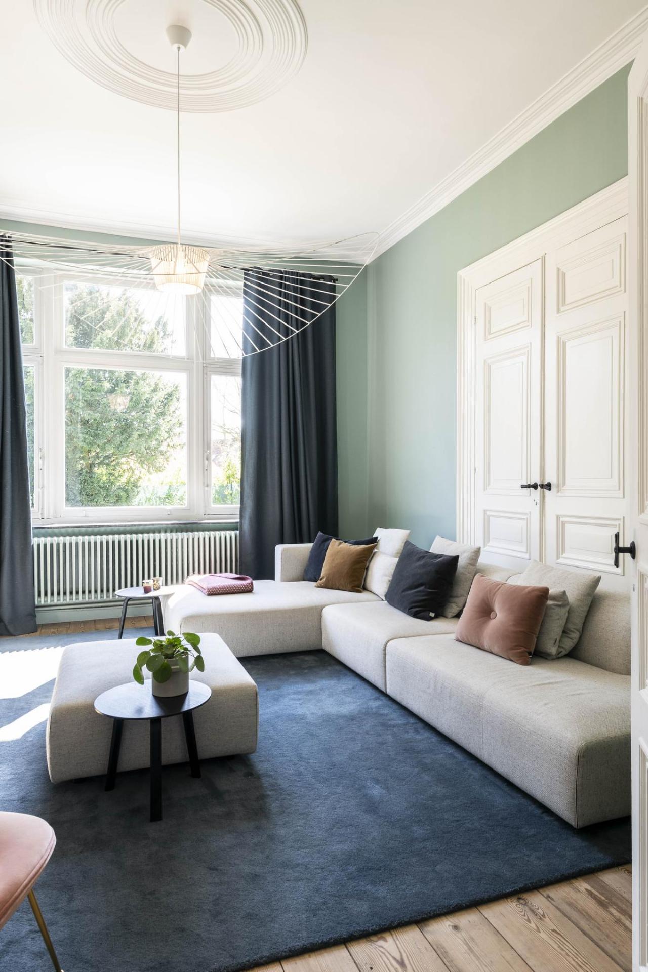 De Vertigo-hanglamp van Petite Friture is een elegante eyecatcher in de woonkamer. Het ontwerp van Constance Guisset wordt gevormd door bijna gewichtloze linten van kunststof en creëert een patroon van zachte schaduwen op de muren en comfortabele zitbank van Prostoria.