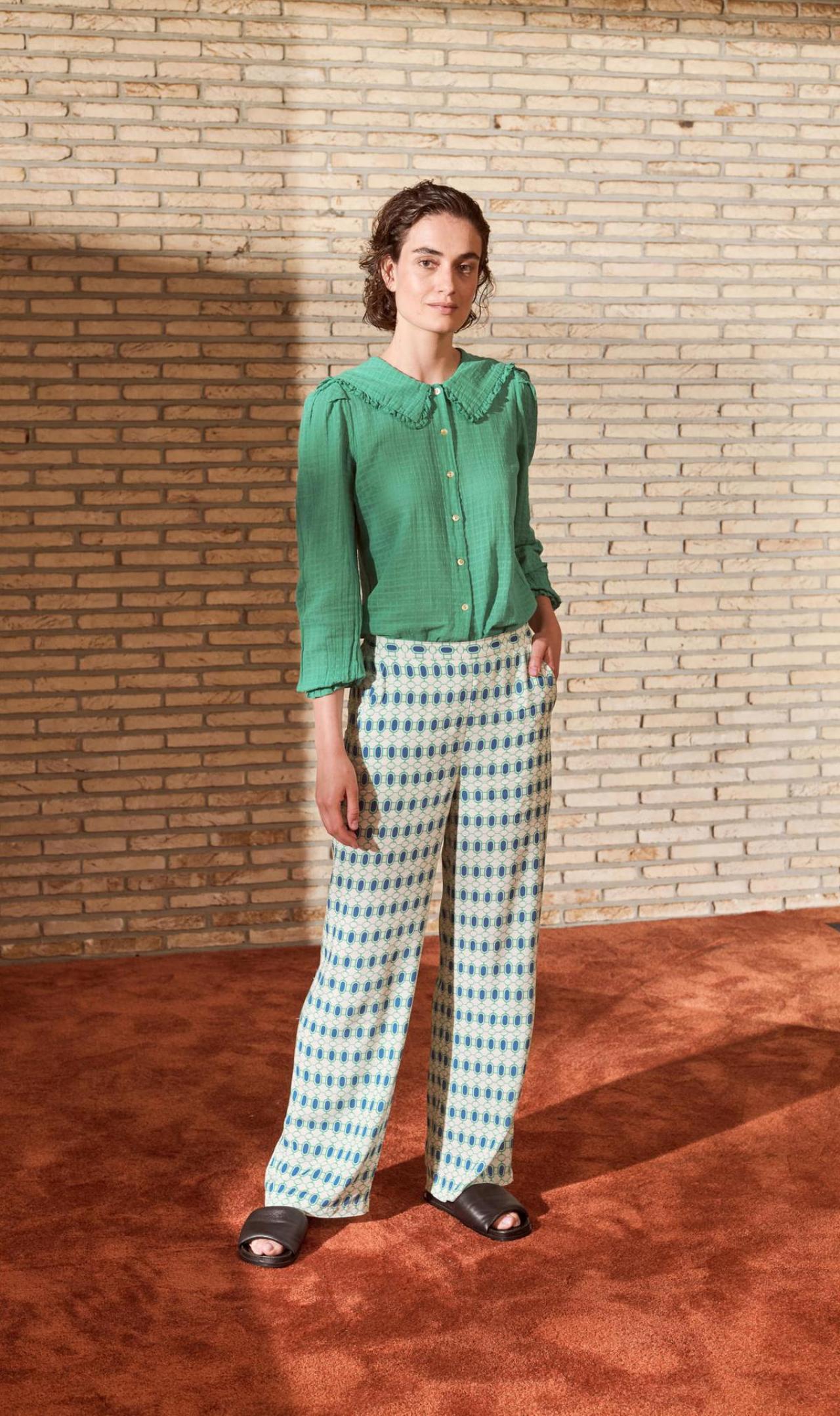 Retro ruchesBloes met ruches aan de kraag (89,99 euro) en pantalon met grafisch motief in wit-blauw-groen (109,99 euro), van Imprévu.