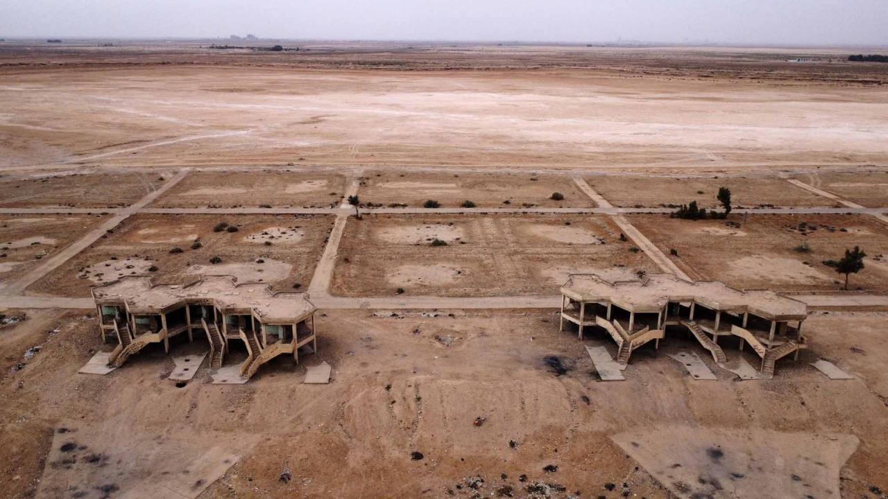 This picture shows abandoned hotels and tourist facilities in Iraq's Sawa Lake which is completely dry due to climate change and rising temperature, in the country's southern province of al-Muthanna on April 19, 2022. - In Sawa, a sharp drop in rainfall -- now only at 30 percent of what used to be normal for the region -- has lowered the underground water table, itself drained by wells, said a senior advisor at Iraq's water resources ministry. (Photo by Asaad NIAZI / AFP)