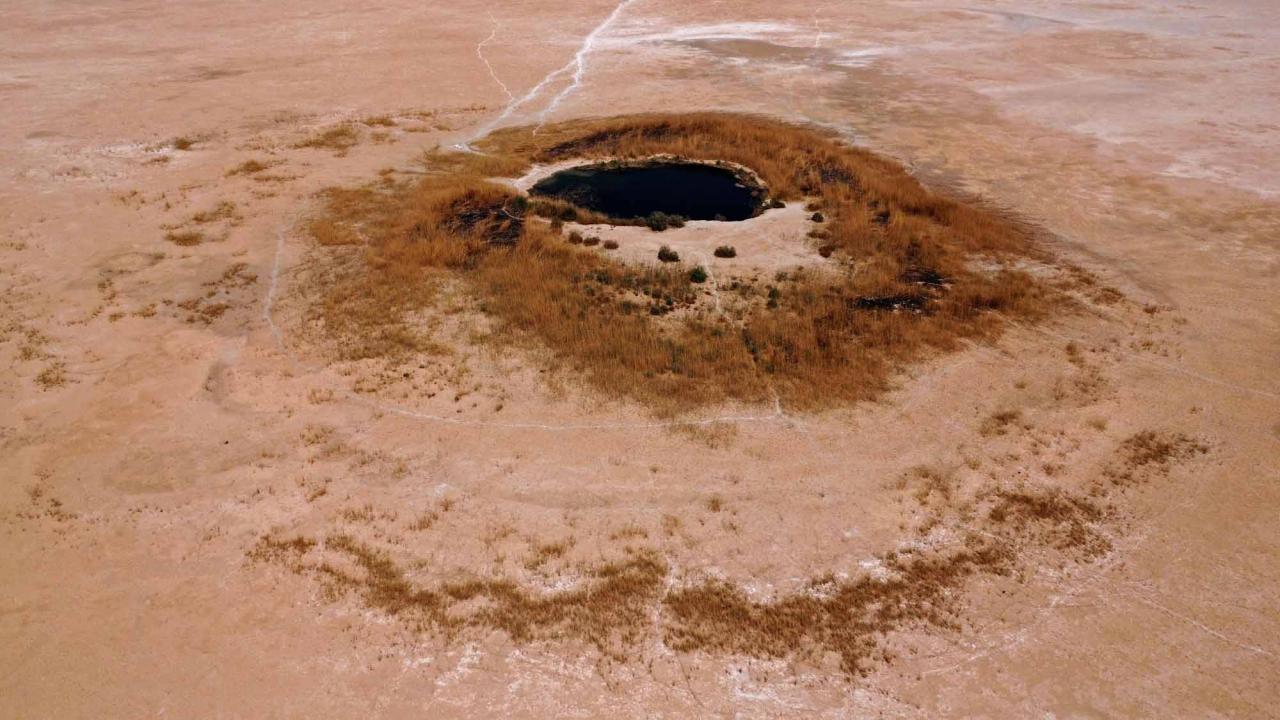 An aerial view shows a pond remaining at the dried-up Sawa Lake in Iraq's southern province of al-Muthanna on April 19, 2022. - In Sawa, a sharp drop in rainfall -- now only at 30 percent of what used to be normal for the region -- has lowered the underground water table, itself drained by wells, said a senior advisor at Iraq's water resources ministry. (Photo by Asaad NIAZI / AFP)