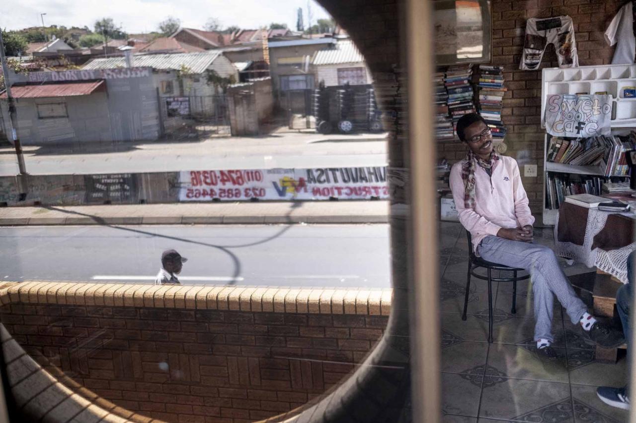The founder of the Soweto Book Cafe, Thami Mazibuko, looks on in his home in Soweto on April 5, 2022. - In Thami Mazibuko's childhood home, the 36-year-old has turned the upper level into a bookstore and library, seeded with 30 of his own books, now overflowing with hundreds of donations.After he finished school, he left Soweto and moved into the formerly white suburbs of Johannesburg, where he stayed with relatives who were artists, with a home full of books.He developed an insatiable appetite for reading, even bring books into the reggae club where liked to listen to music.When he decided to move back home, he brought his growing personal collection with him.So began the Soweto Book Cafe, officially founded in 2018. (Photo by EMMANUEL CROSET / AFP)