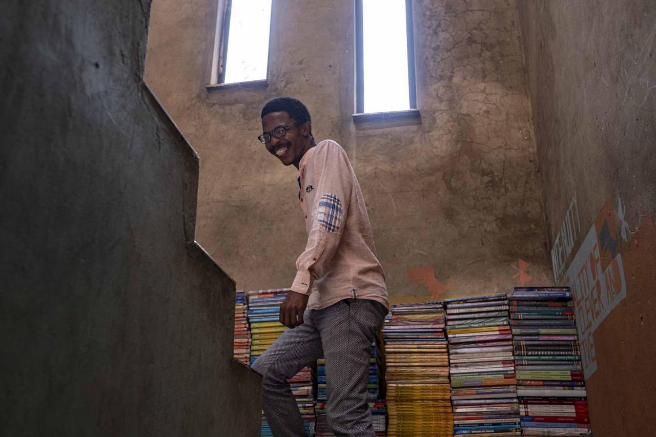 Founder of the Soweto Book Café, Thami Mazibuko, 36, walks up the stairs of his home in Soweto on April 5, 2022. - In Thami Mazibuko's childhood home, the 36-year-old has turned the upper level into a bookstore and library, seeded with 30 of his own books, now overflowing with hundreds of donations.
After he finished school, he left Soweto and moved into the formerly white suburbs of Johannesburg, where he stayed with relatives who were artists, with a home full of books.
He developed an insatiable appetite for reading, even bring books into the reggae club where liked to listen to music.
When he decided to move back home, he brought his growing personal collection with him.
So began the Soweto Book Cafe, officially founded in 2018. (Photo by EMMANUEL CROSET / AFP)