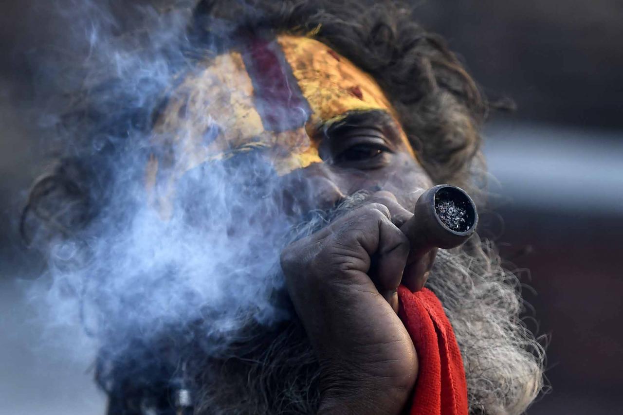 This photograph taken on April 27, 2022, shows a Sadhu (Hindu holy man) smoking marijuana using a traditional clay pipe at Pashupatinath Temple in Kathmandu. - Nepal's marijuana ban could soon be up in smoke, as lawmakers mull a return to the liberal drug policies that once made the Himalayan republic a popular pit stop on the overland "Hippie Trail". (Photo by Prakash MATHEMA / AFP) / TO GO WITH 'Nepal-law-cannabis-drugs' FOCUS