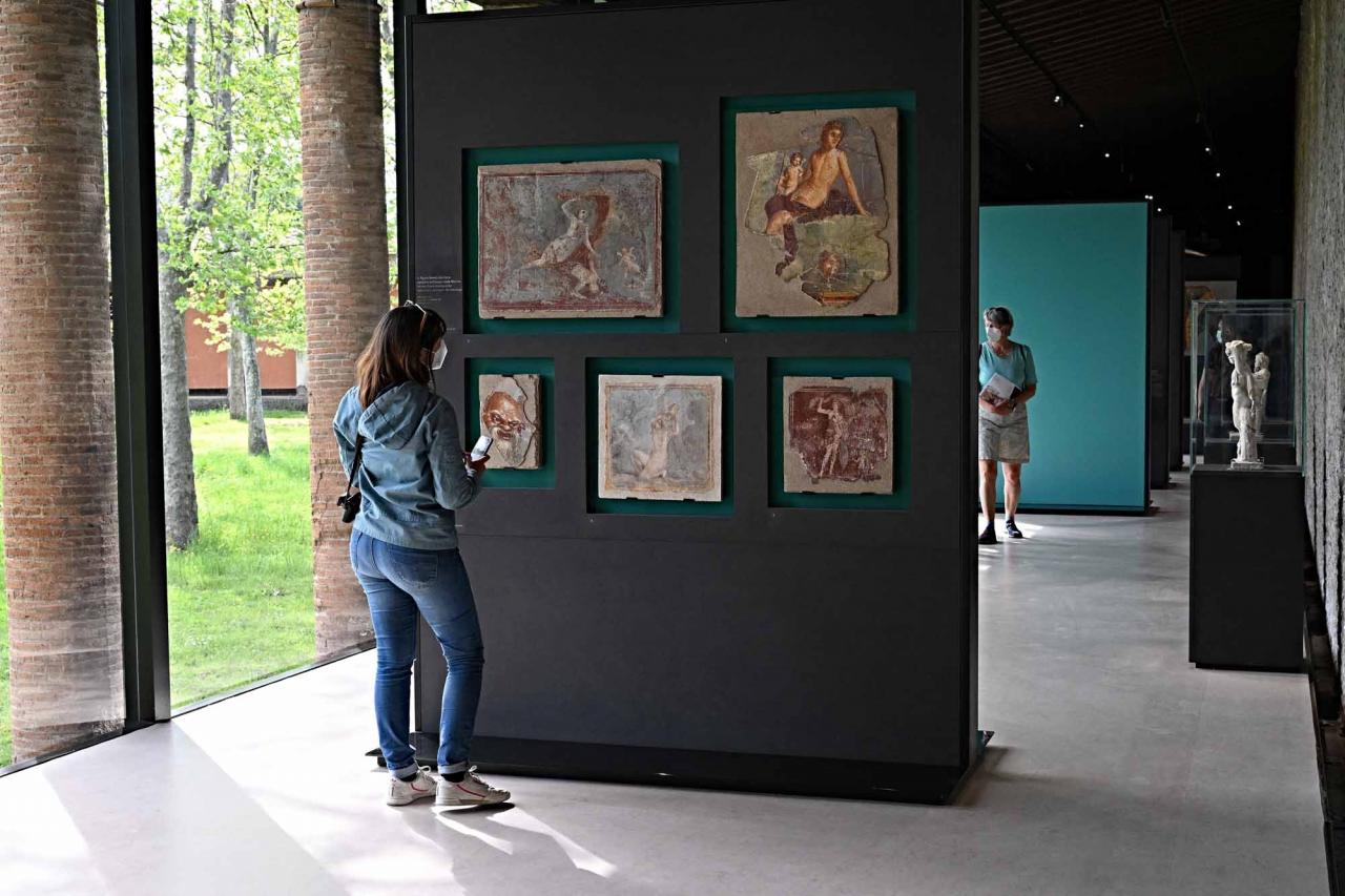 Visitors attend a new exhibition in Pompeii's site entitled "Art and sensuality in the houses of Pompeii" on art and sexuality in the ancient city, where sculptures and paintings of breasts and buttocks abounded, on April 28, 2022. - Raunchy scenes may redden faces at a new exhibition in Pompeii on art and sexuality in the ancient Roman city, where sculptures and paintings of breasts and buttocks abounded. Archaeologists excavating the city, which was destroyed by the eruption of nearby Vesuvius in 79 AD, were initially startled to discover erotic images everywhere, from garden statues to ceiling frescos. (Photo by Andreas SOLARO / AFP)