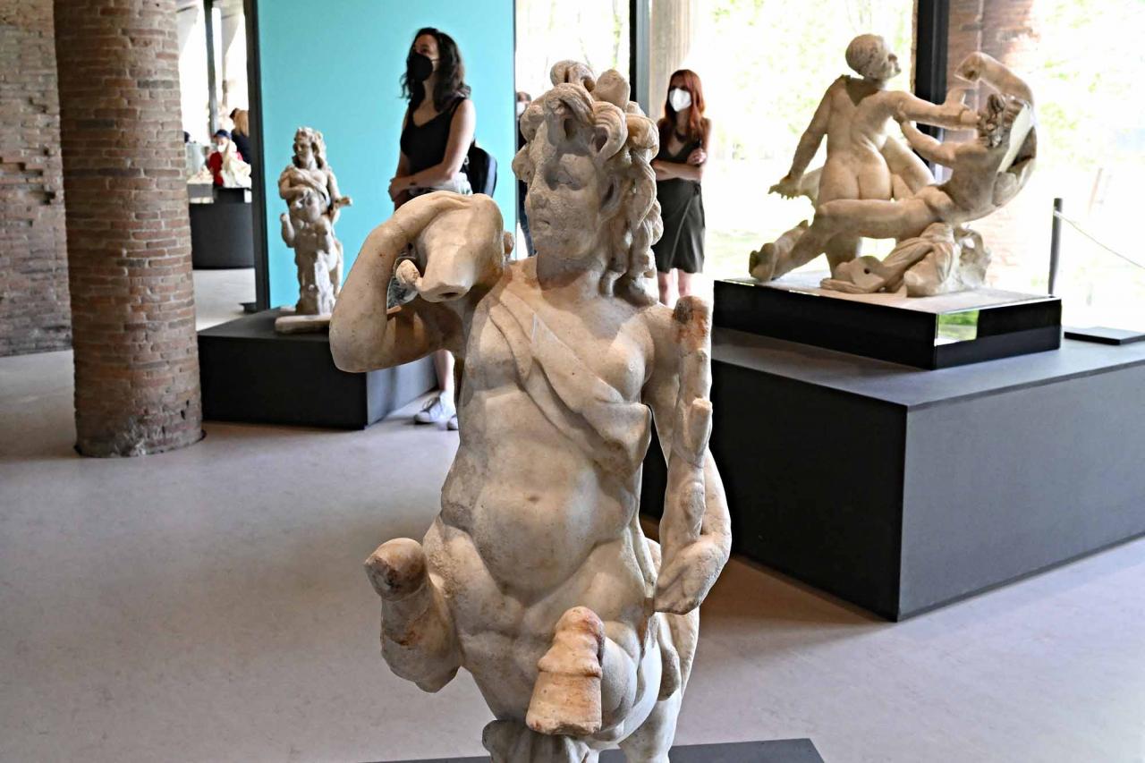 Vistors walk next to a "Centauress with fawn" sculpture, in Pompeii's site during a new exhibition entitled "Art and sensuality in the houses of Pompeii" on art and sexuality in the ancient city, where sculptures and paintings of breasts and buttocks abounded, on April 28, 2022. - Raunchy scenes may redden faces at a new exhibition in Pompeii on art and sexuality in the ancient Roman city, where sculptures and paintings of breasts and buttocks abounded. Archaeologists excavating the city, which was destroyed by the eruption of nearby Vesuvius in 79 AD, were initially startled to discover erotic images everywhere, from garden statues to ceiling frescos. (Photo by Andreas SOLARO / AFP)
