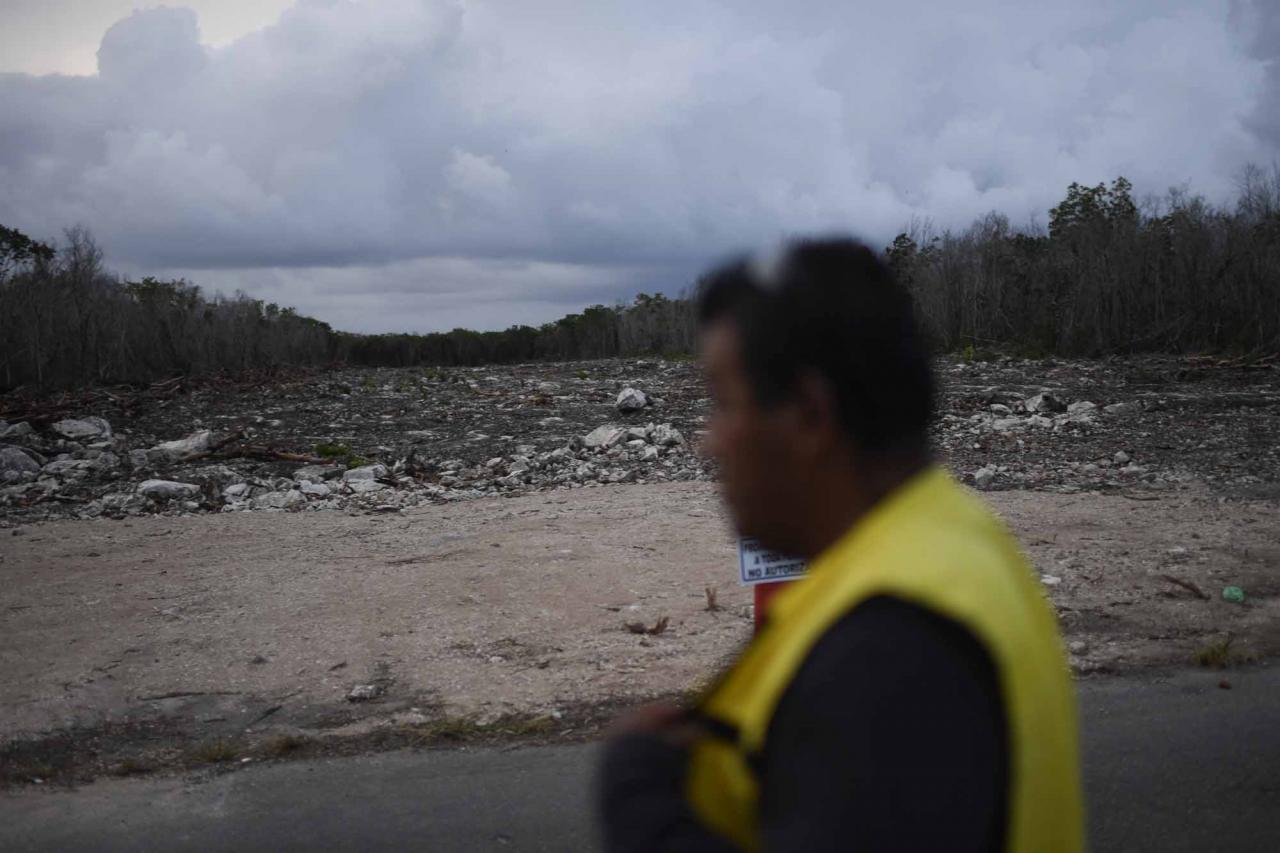 A security guard walks at the construction site of Section 5 South of the Mayan Train between the resorts of Playa del Carmen and Tulum which was halted by a district judge pending resolution of an injunction sought by scuba divers and environmentalists -- in the jungle in Playa del Carmen, Quintana Roo State, Mexico, on April 26, 2022. - A Mexican judge earlier this month suspended construction of part of President Andres Manuel Lopez Obrador's flagship tourist train project in the Yucatan peninsula due to a lack of environmental impact studies. The Mayan Train, a roughly 1,500-kilometre (950 mile) rail loop linking popular Caribbean beach resorts and archeological ruins, has met with opposition from environmentalists and indigenous communities. (Photo by Pedro PARDO / AFP)